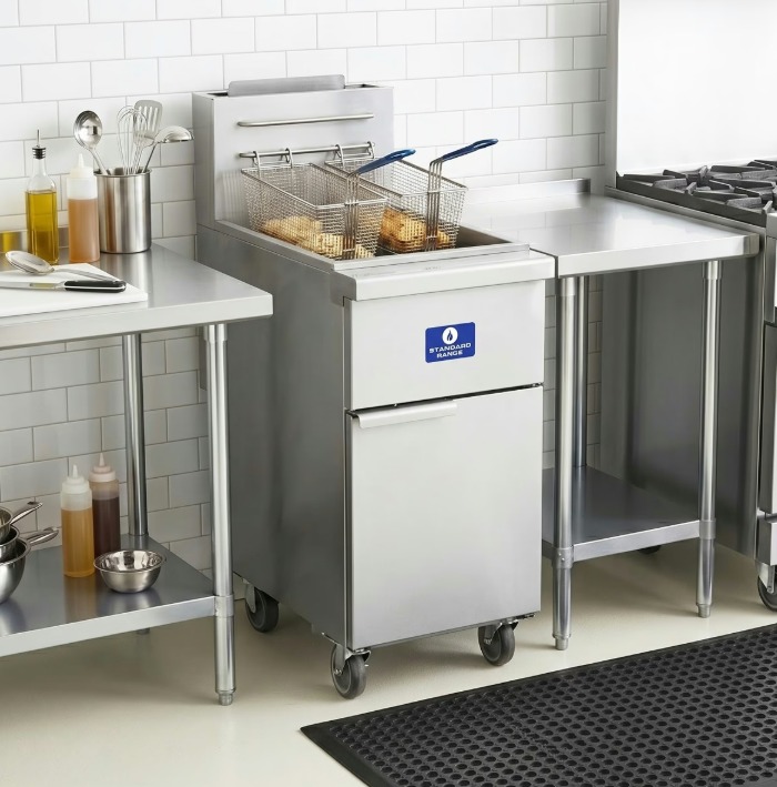 Two small baskets full of food cooking inside a tall, metal commercial fryer in a restaurant kitchen.