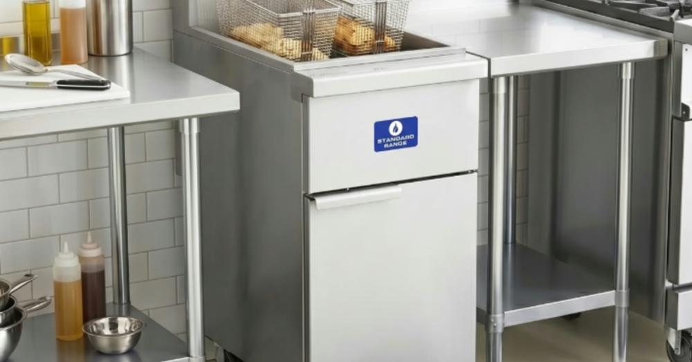 A commercial fryer installed against a wall in a restaurant kitchen. Both fryer baskets in the machine are full of food.