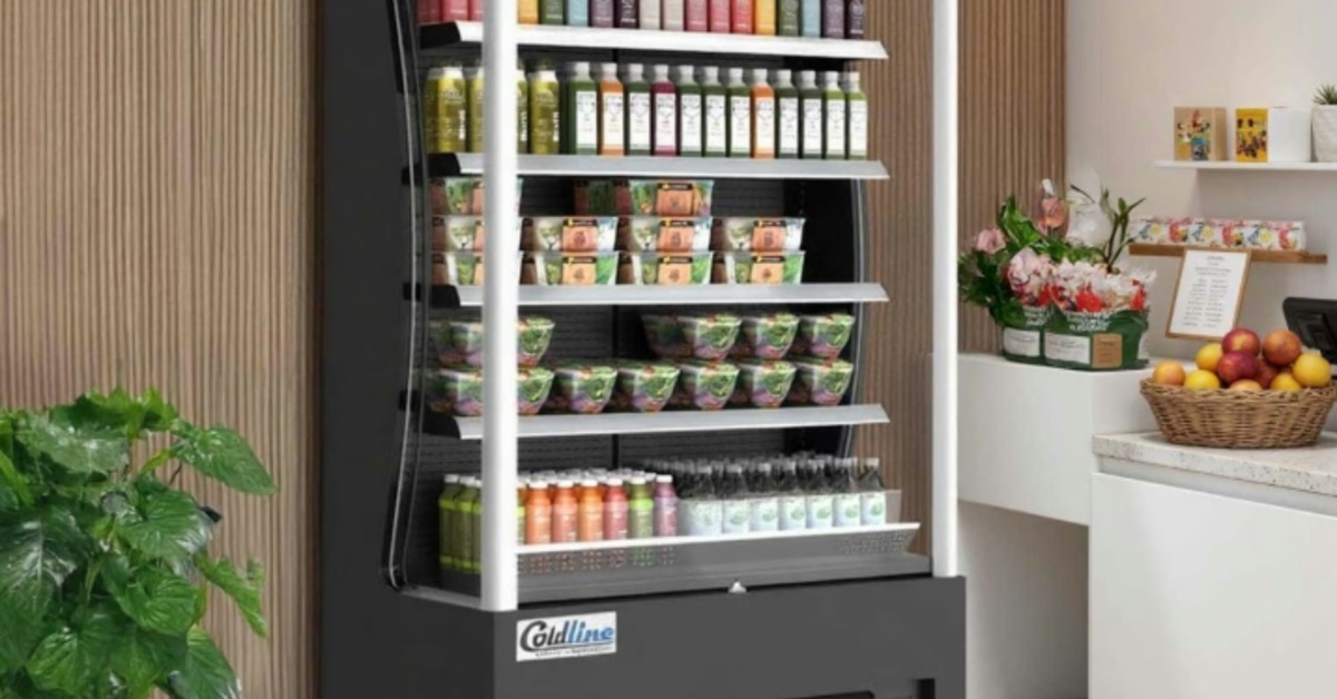 A tall open air cooler in front of a brown wall in a brightly lit grocery store. The cooler is full of food and drinks.