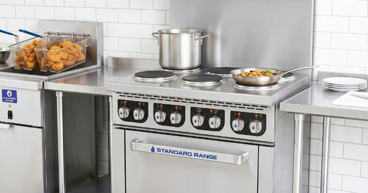 A commercial electric stovetop at the back of a restaurant kitchen. A pan of food sits on the stove.