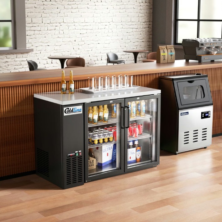 Two undercounter fridges installed against a wooden bar in a brightly lit shop. Two beers sit on the fridges.